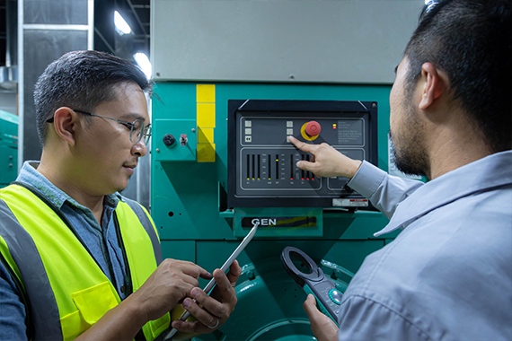 Technicians Monitoring Generator Control Panel With Testing Tools