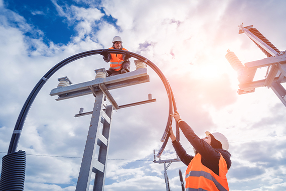 Utility Workers Installing Overhead Power Line On Electric Poles