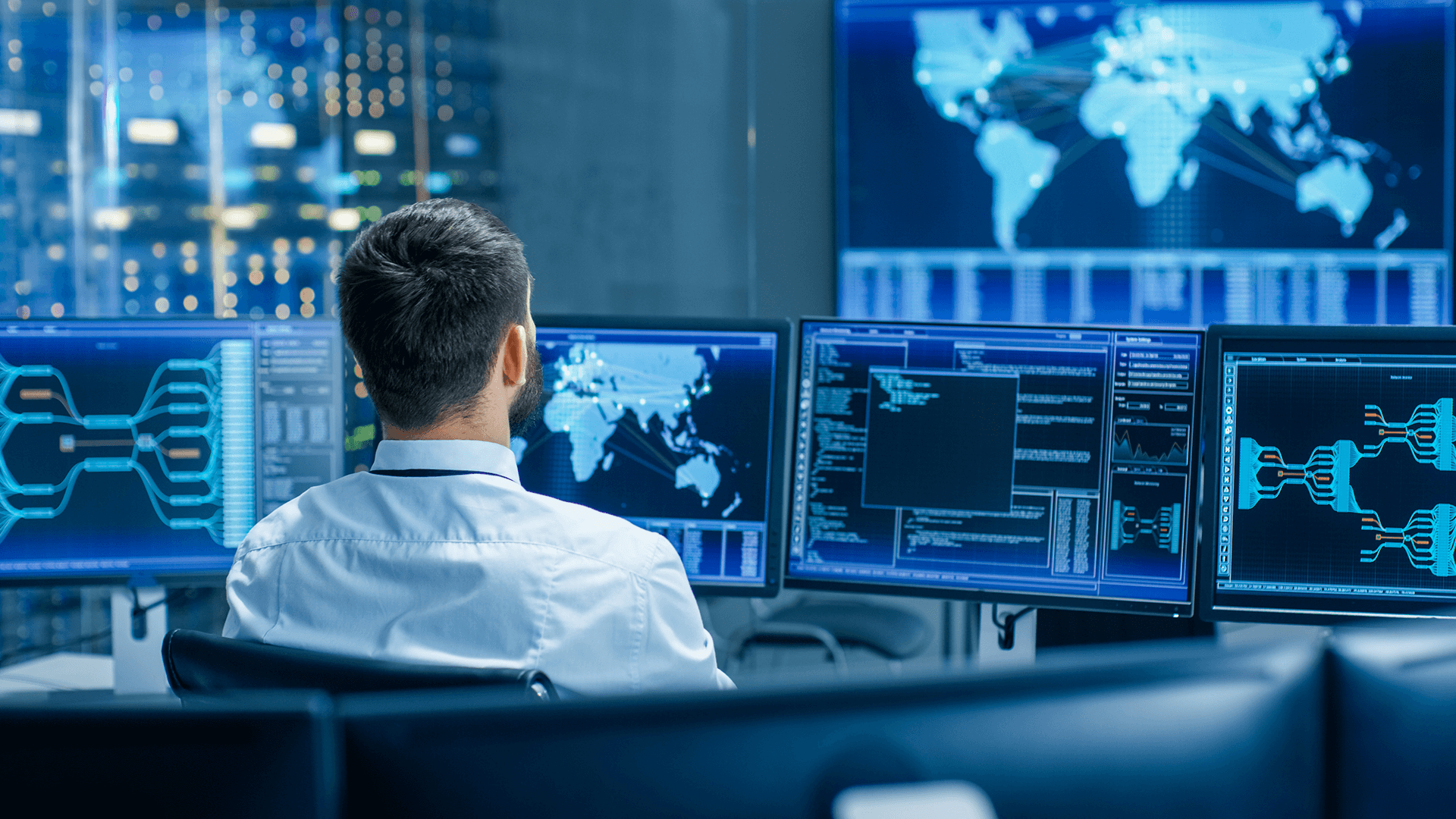 back view of a person looking at multiple computer screens in a data center